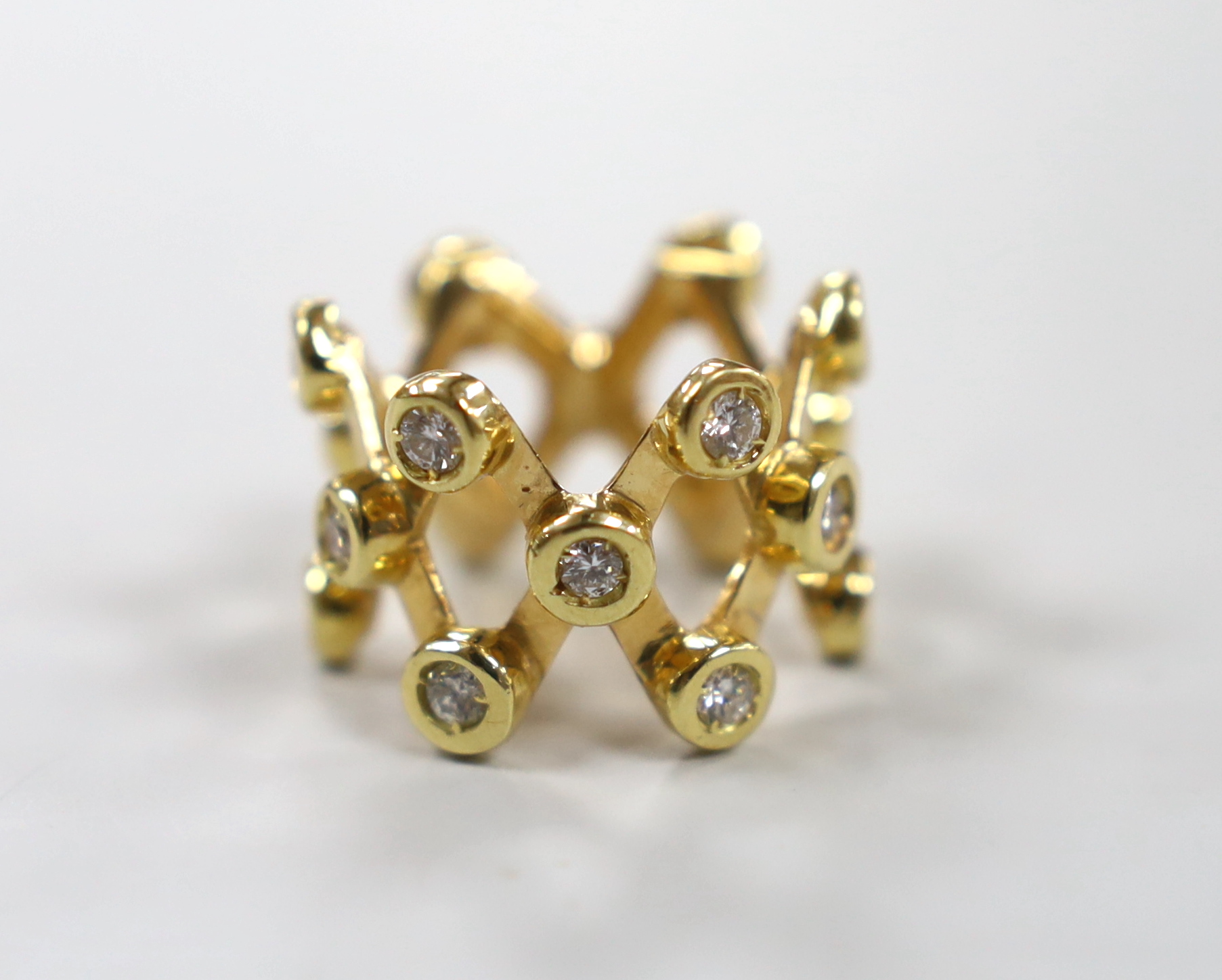 A modern yellow metal and diamond cluster set lattice work dress ring, size L/M, gross weight 12.7 grams.